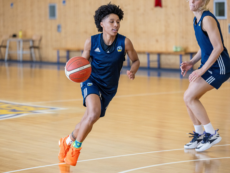 Eine Basketballspielerin von Alba Berlin dribbelt und geht an einer anderen Spielerin vorbei.