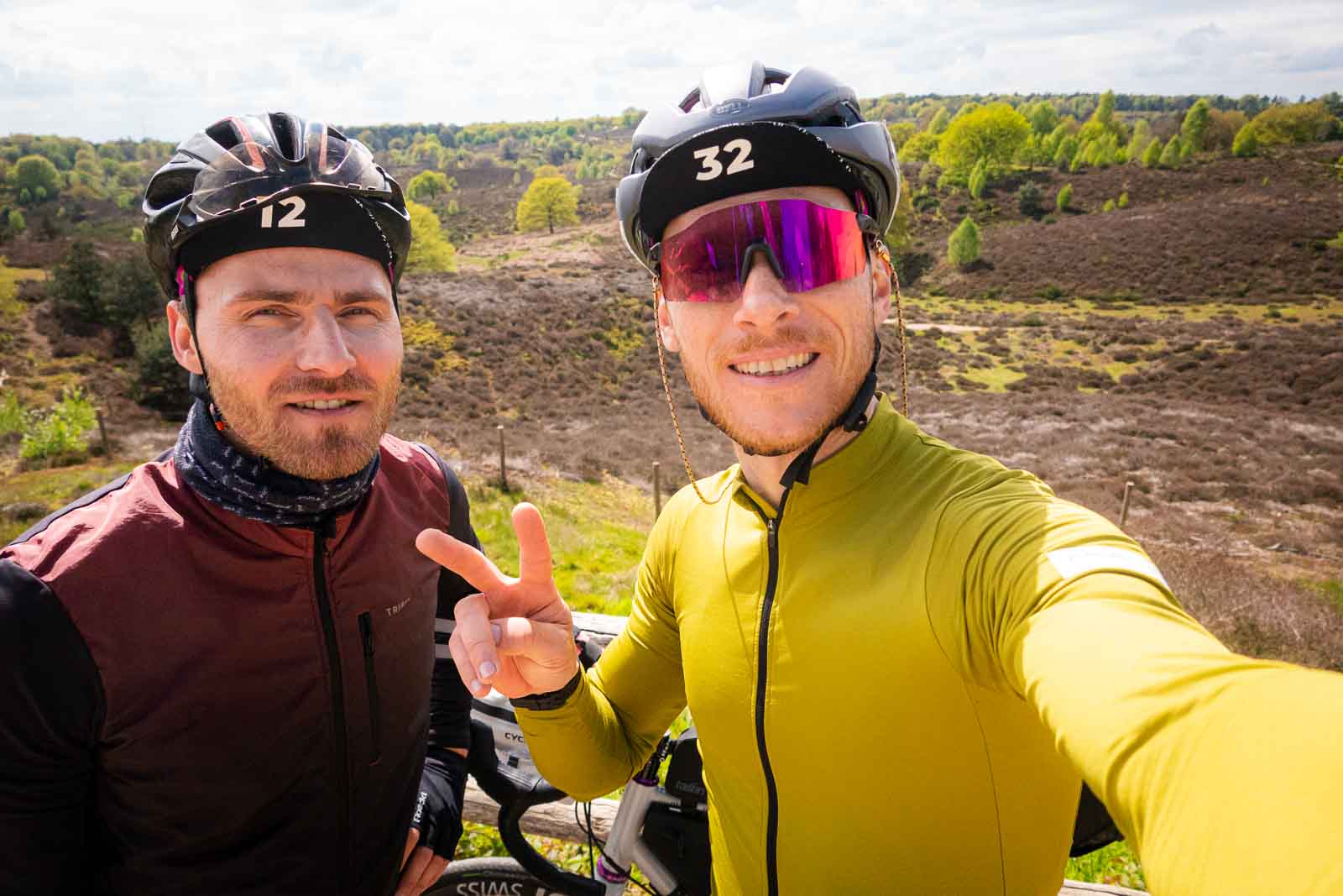 Zwei Radfahrer stehen vor einer prachtvollen Heidelandschaft und machen Selfie